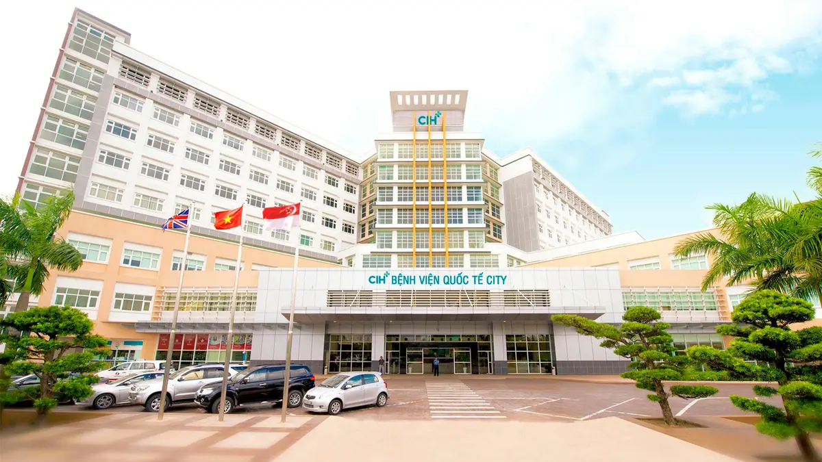 City International Hospital building with flags above the entrance and a car park in front.