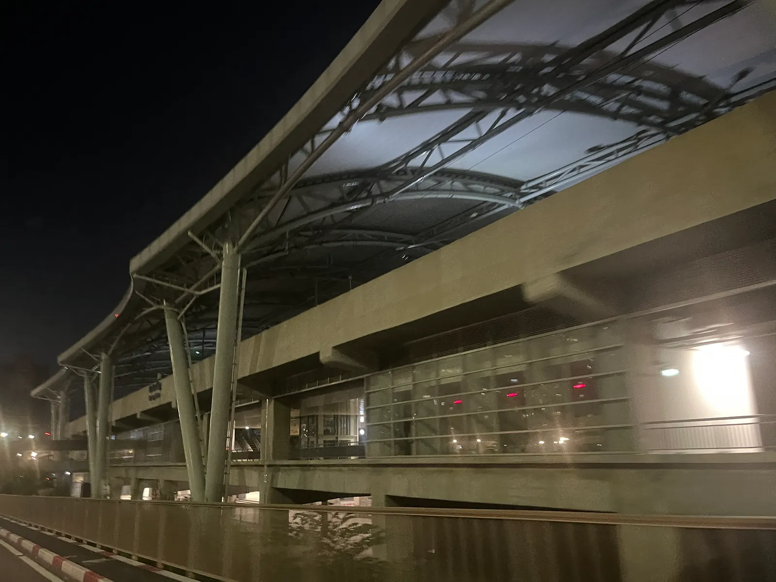 Steel-roofed elevated metro station lit at night