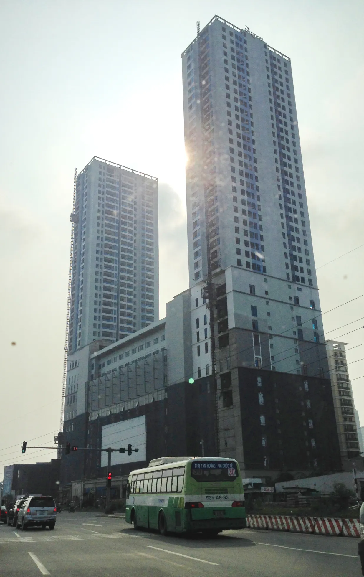 Tall apartment towers with a green city bus passing on the street below.