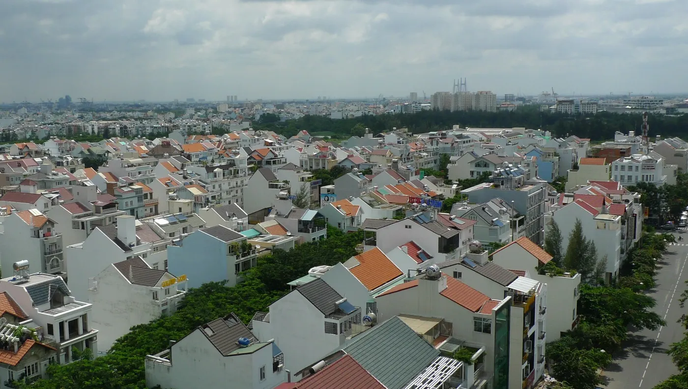 View over rows of terraced townhouses with orange roofs and tree-lined streets in a planned district