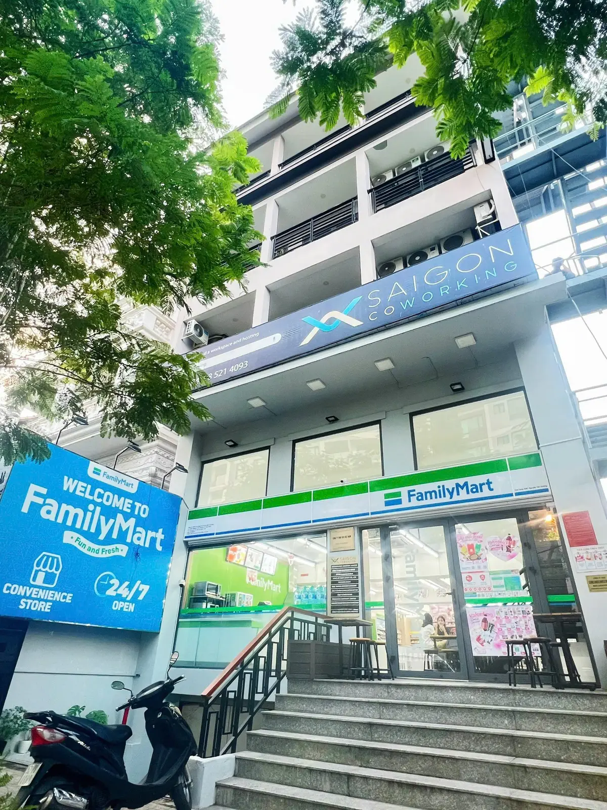 Building front with a blue Saigon Coworking sign above a convenience store