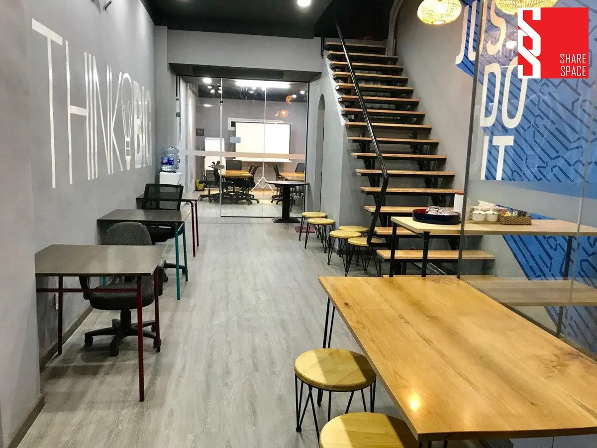 Narrow room with long wooden desks, stools and a staircase