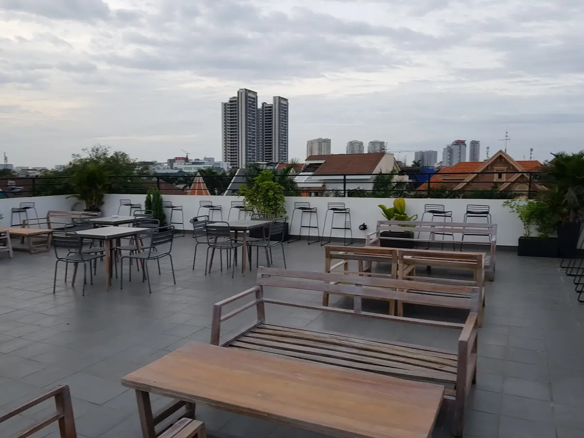 Roof terrace with wooden tables, benches and chairs and a view of apartment towers