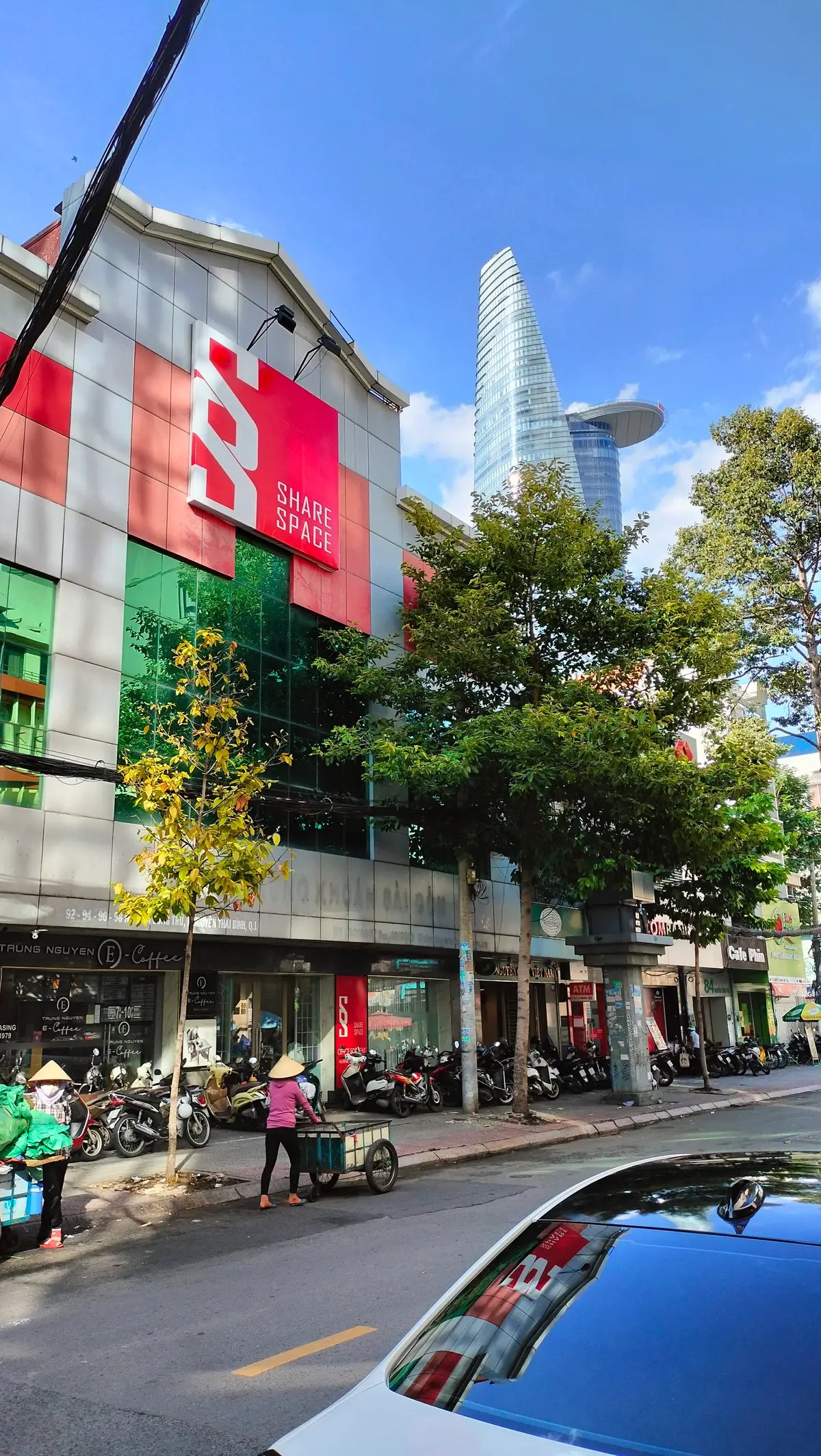 Office building front with a red Sharespace sign above street-level shops