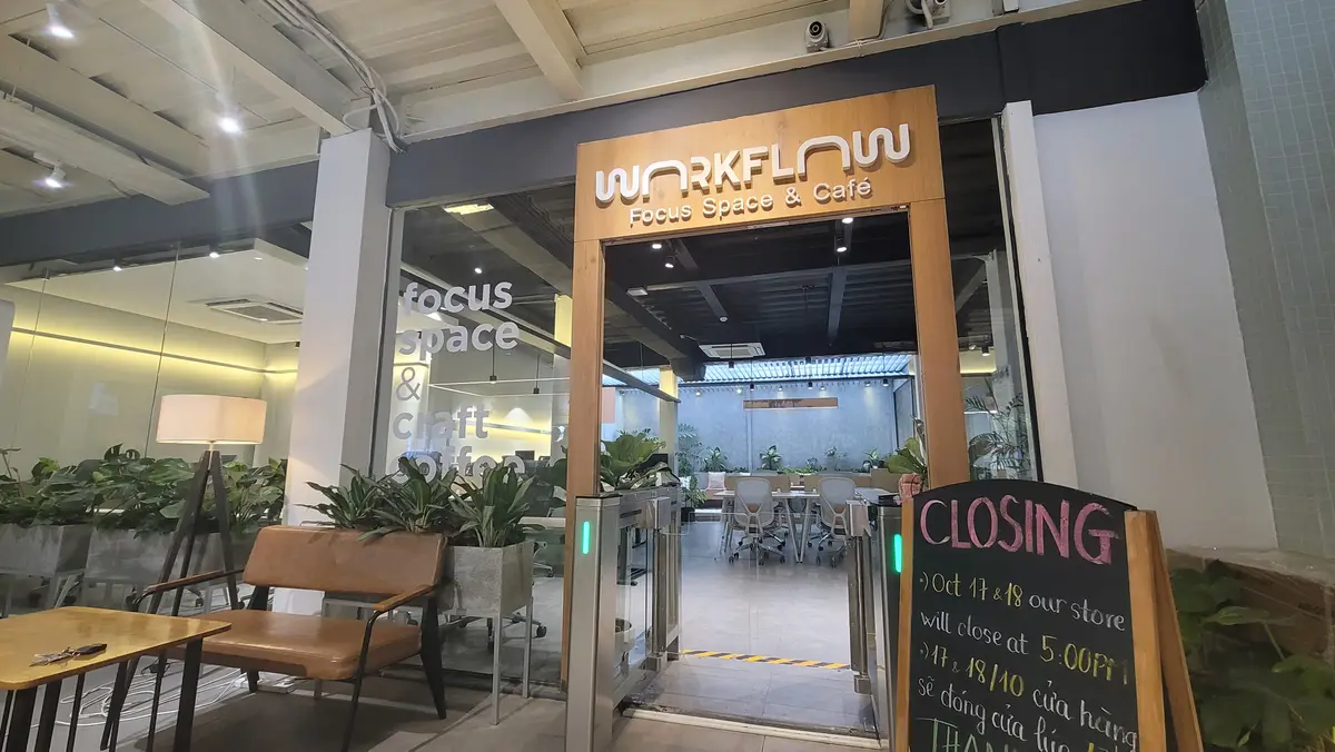 Cafe-style entrance with a wooden frame sign and plants