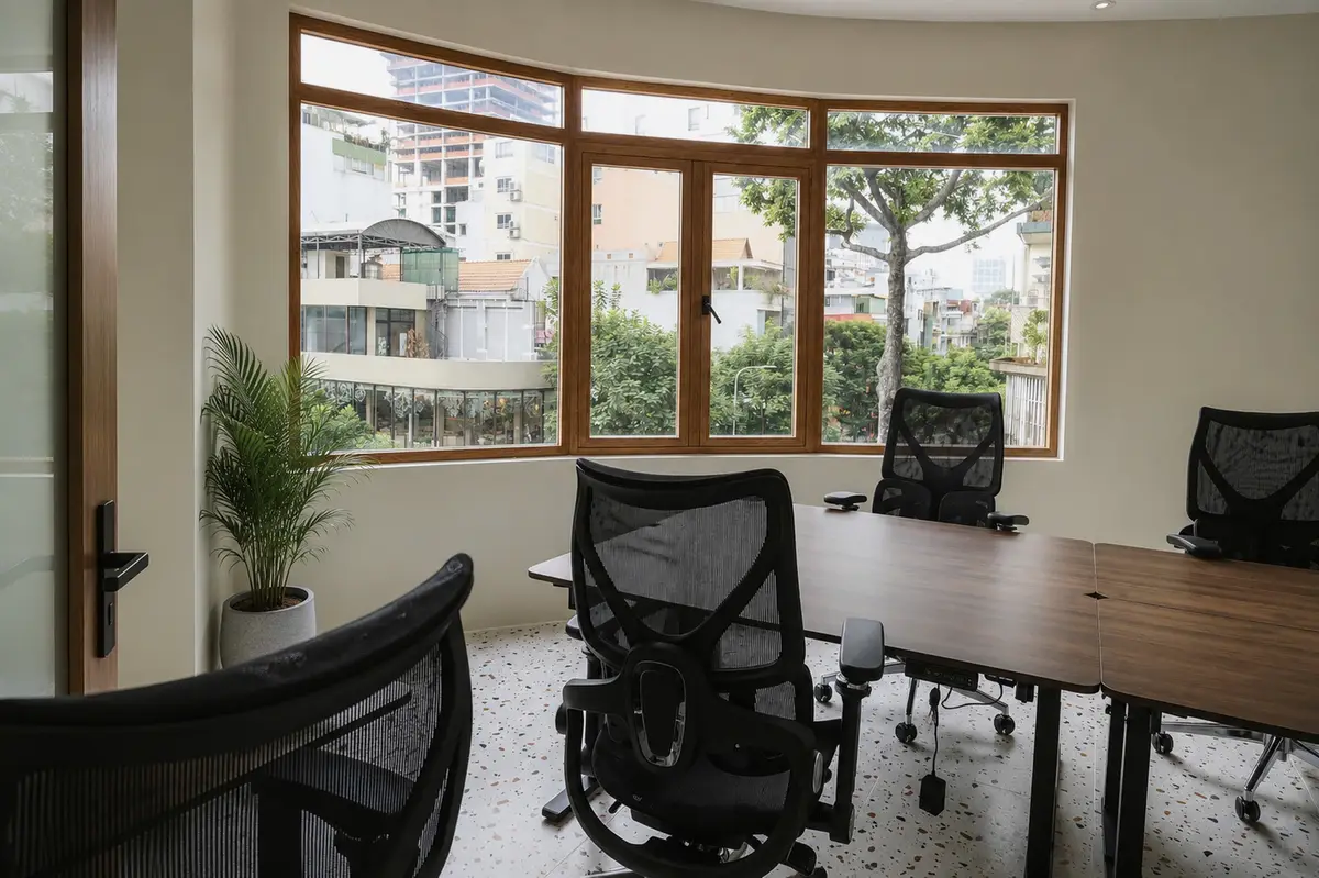 Meeting table with black office chairs beside windows with street views