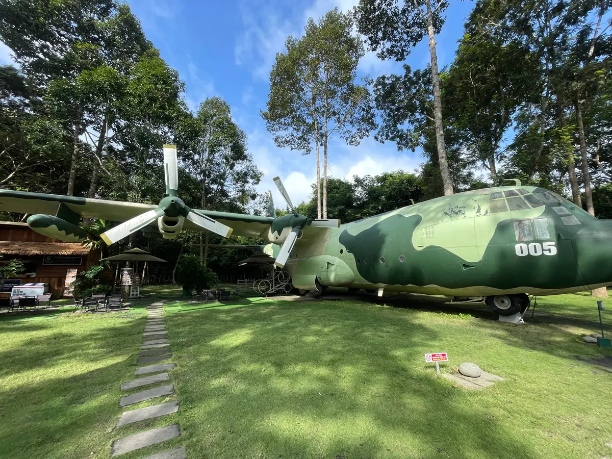 Green camouflaged aircraft with propellers on display on a lawn among trees