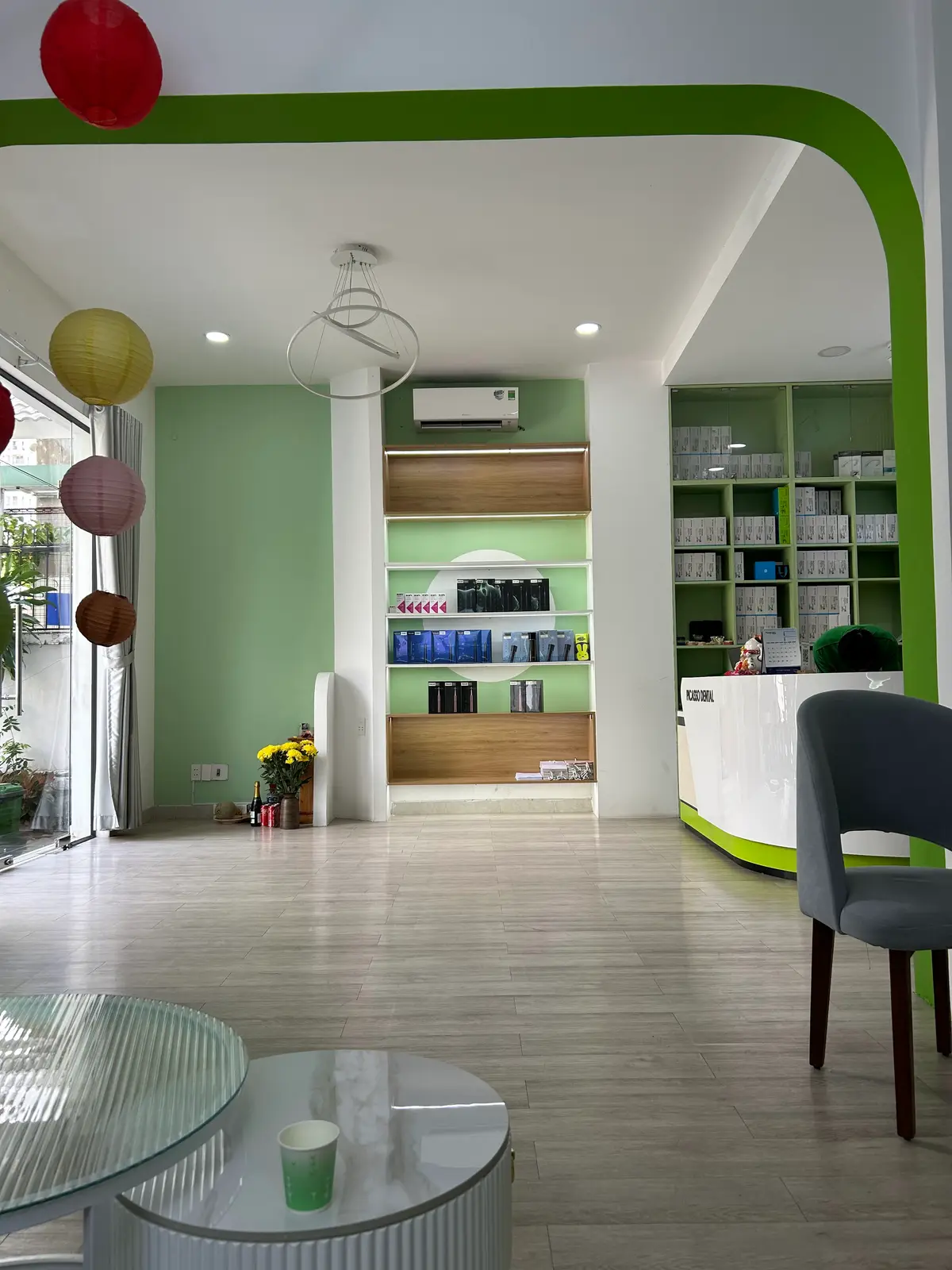 Bright green and white reception room with shelves of dental products and a curved front desk.