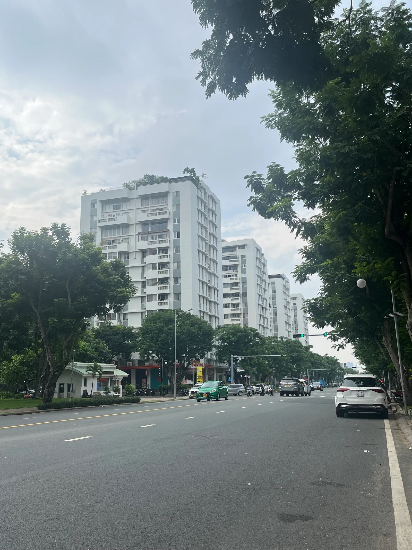 Wide street with white apartment towers and trees on a clear day