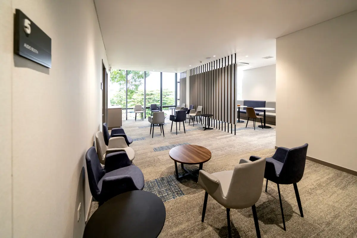 Raffles Medical waiting lounge with armchairs, round tables and large windows.