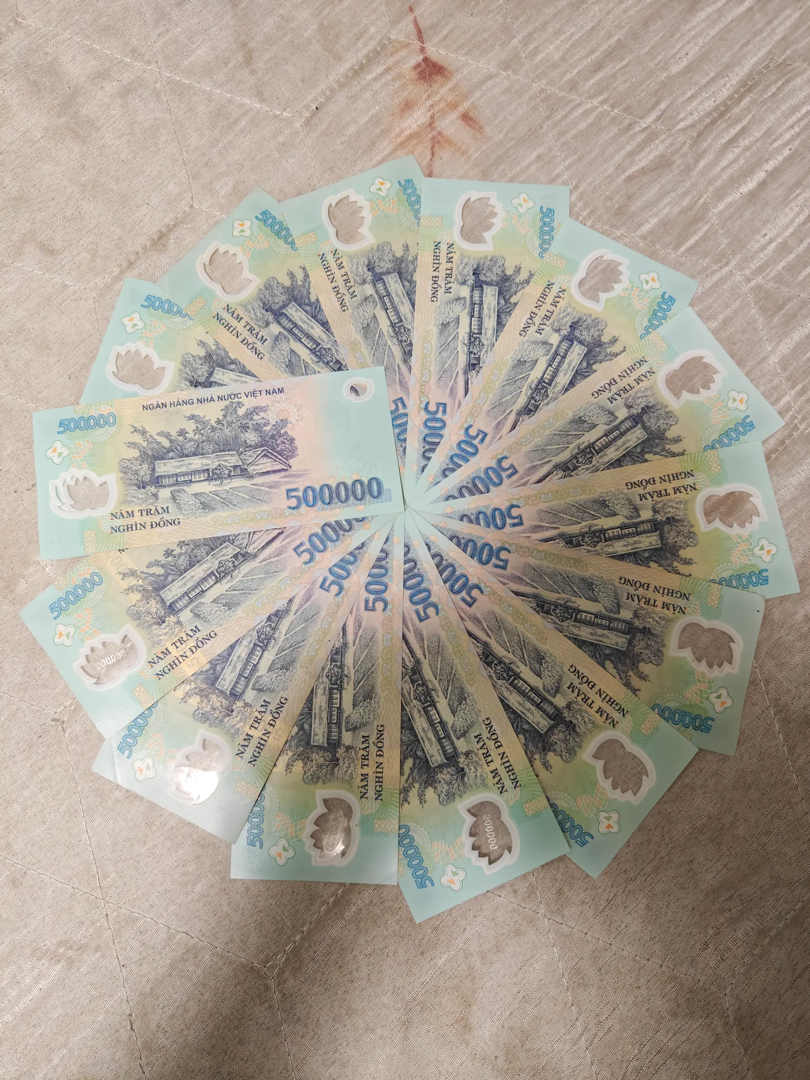 Fan of Vietnamese banknotes in light blue and green laid in a circle on a table