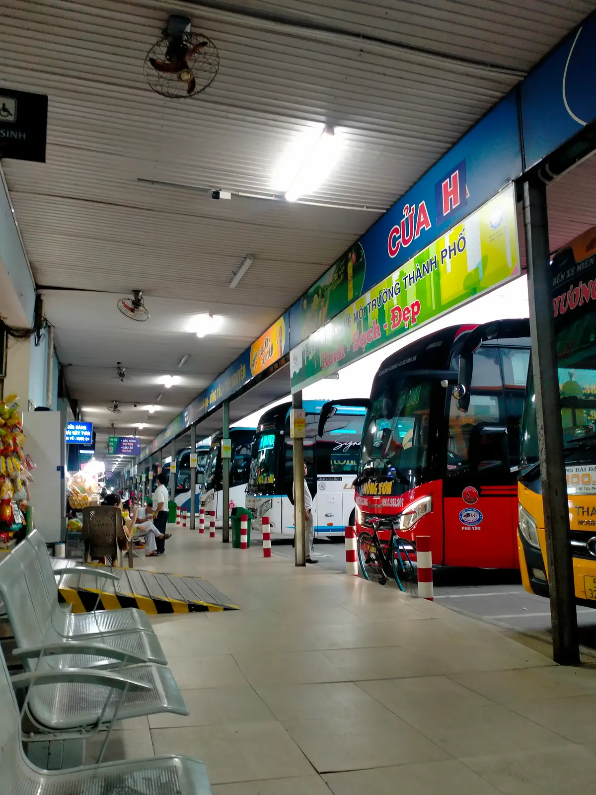 Red coaches lined up under a long covered bay with colourful destination boards