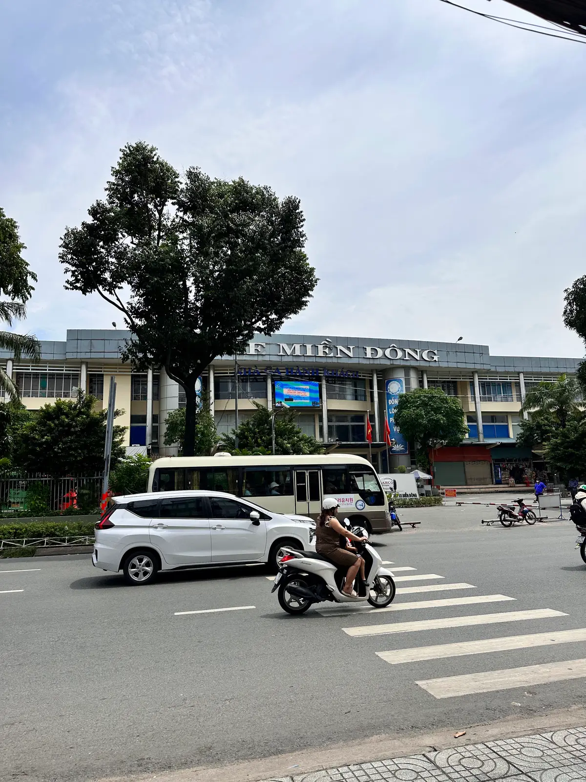 Old Mien Dong station building with its name on the roof, seen across a street with a white minibus