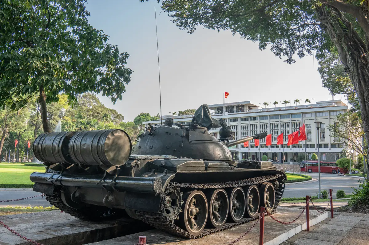 Dark green tank with a gun barrel parked on a paved yard in front of the palace