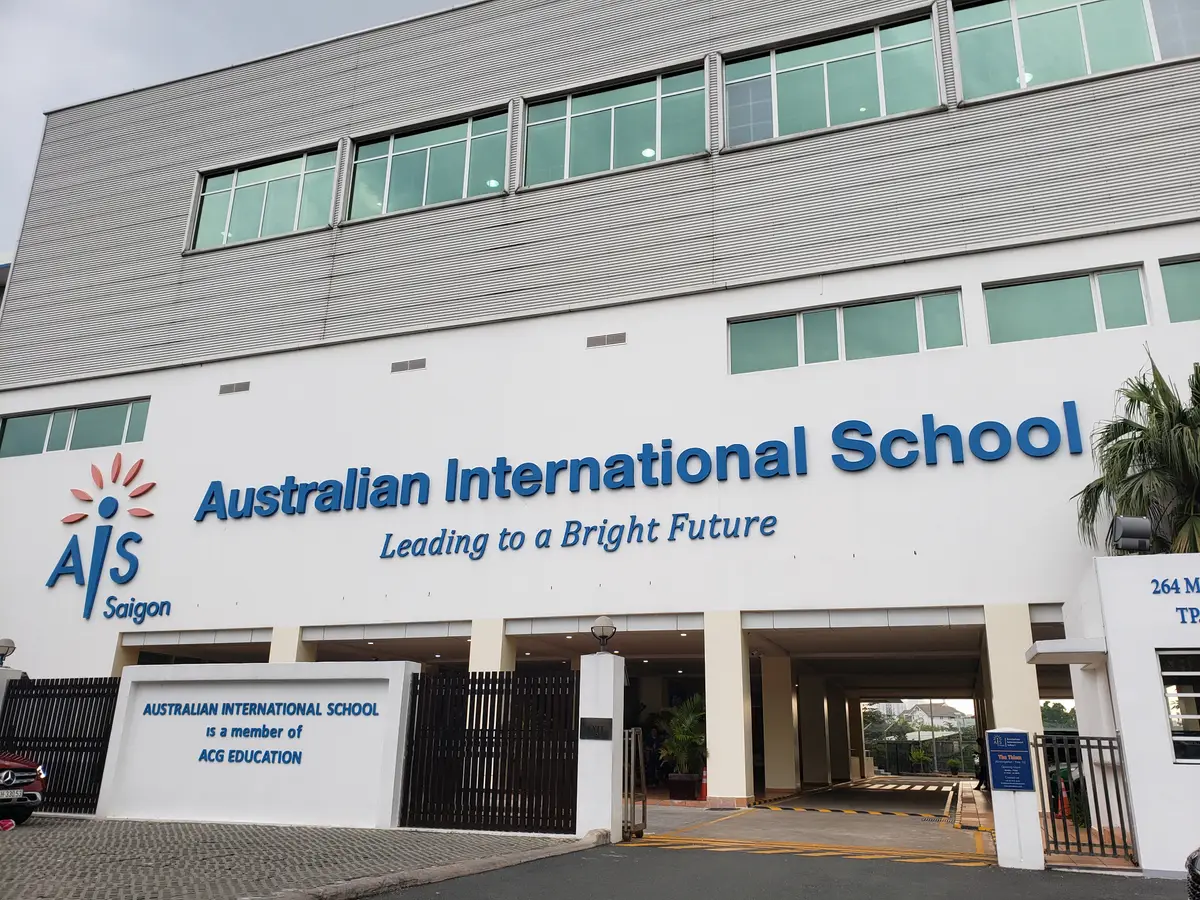 School front with a blue and white name sign above a gate