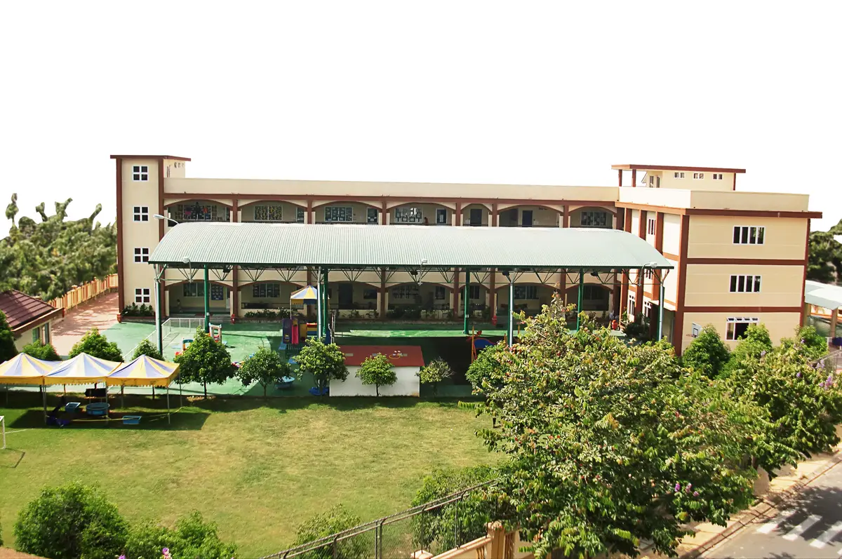Low school buildings with tiled roofs behind a green lawn