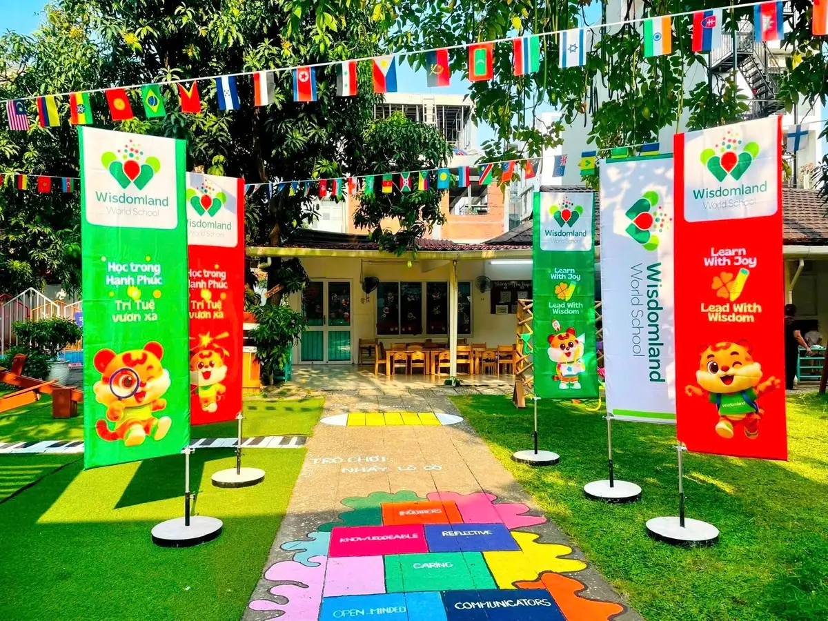 Tall school banners and a painted hopscotch path on a lawn in front of a low building
