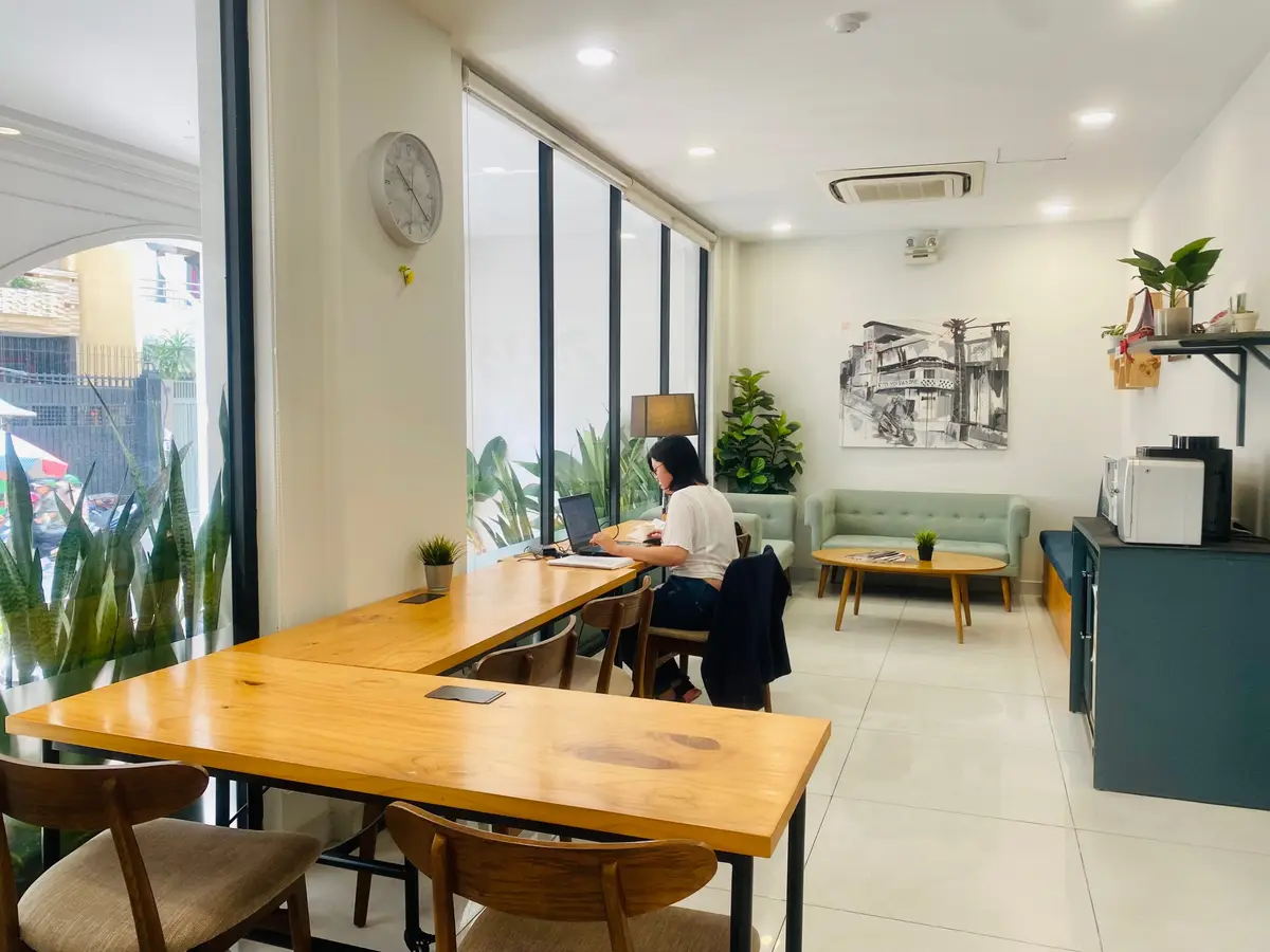 Lounge corner with a long wooden table, sofa and large windows