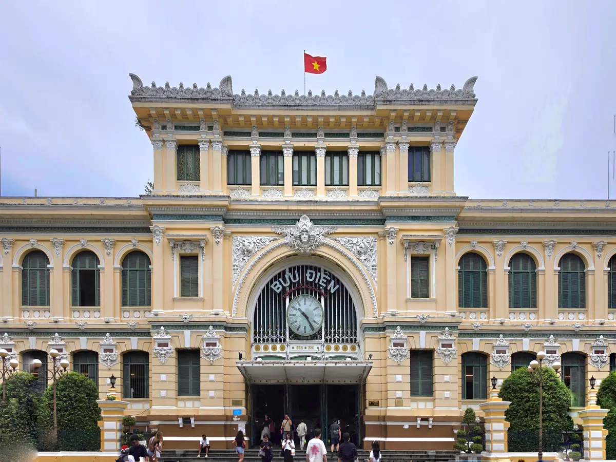 Cream post office facade with a clock above the entrance and a red flag on the roof