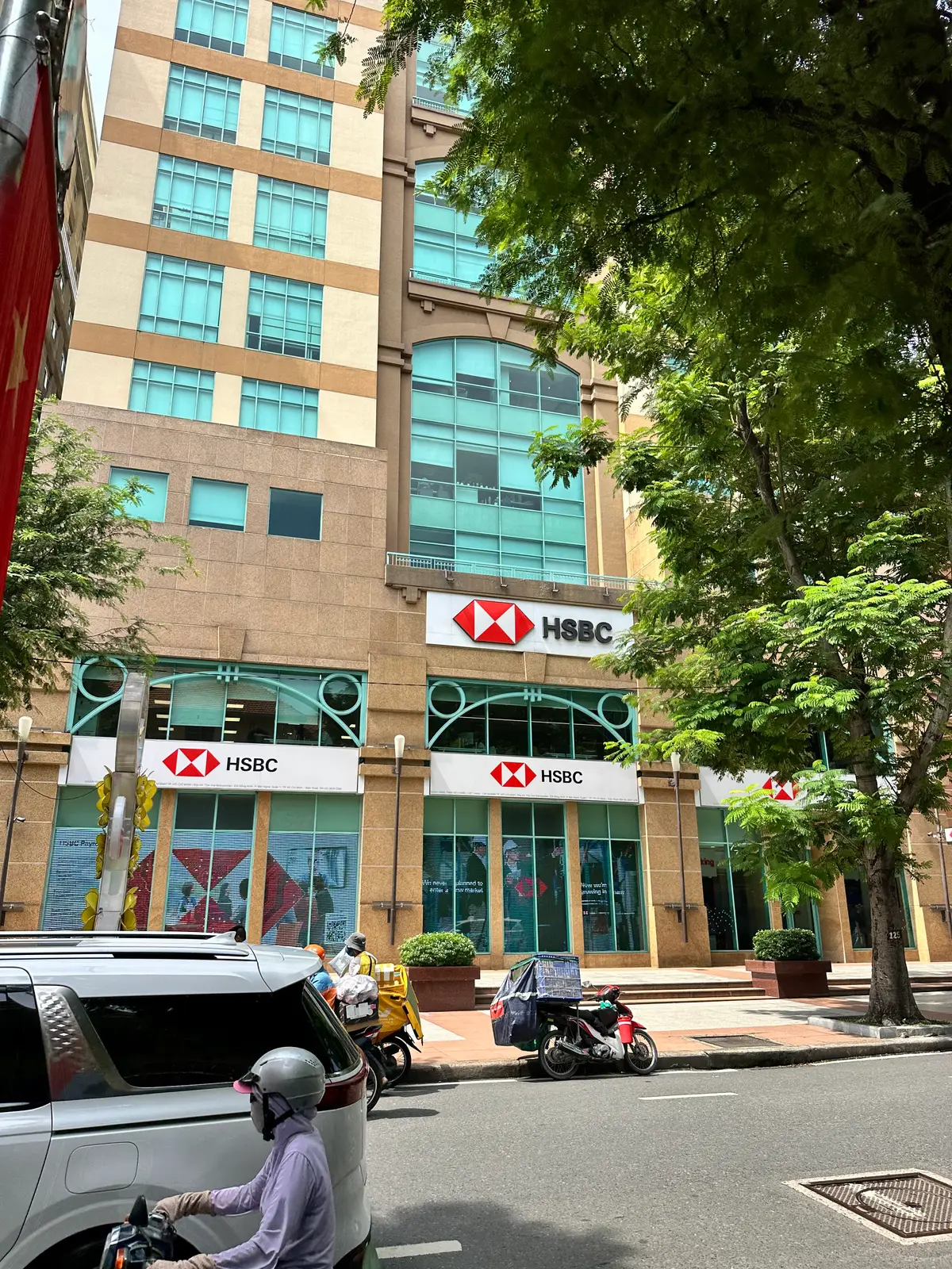 HSBC office building with tree-lined pavement and red HSBC signs on the ground floor.