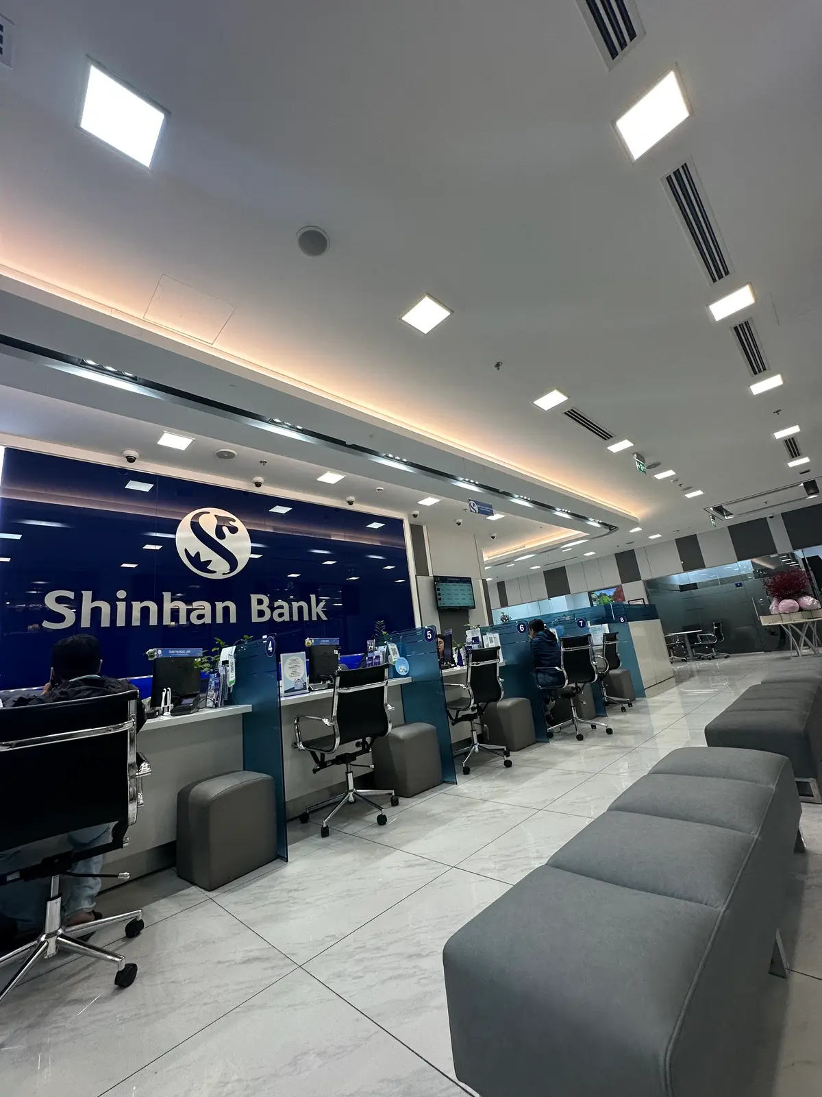 Shinhan Bank branch interior with blue service counters and waiting seats.