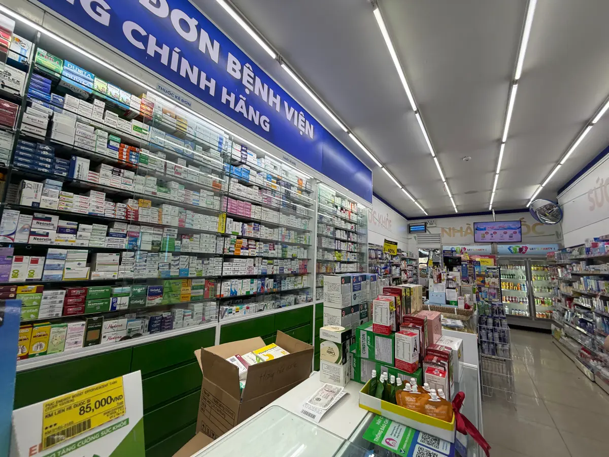 Long aisle of shelves packed with boxed medicines inside a Pharmacity store.