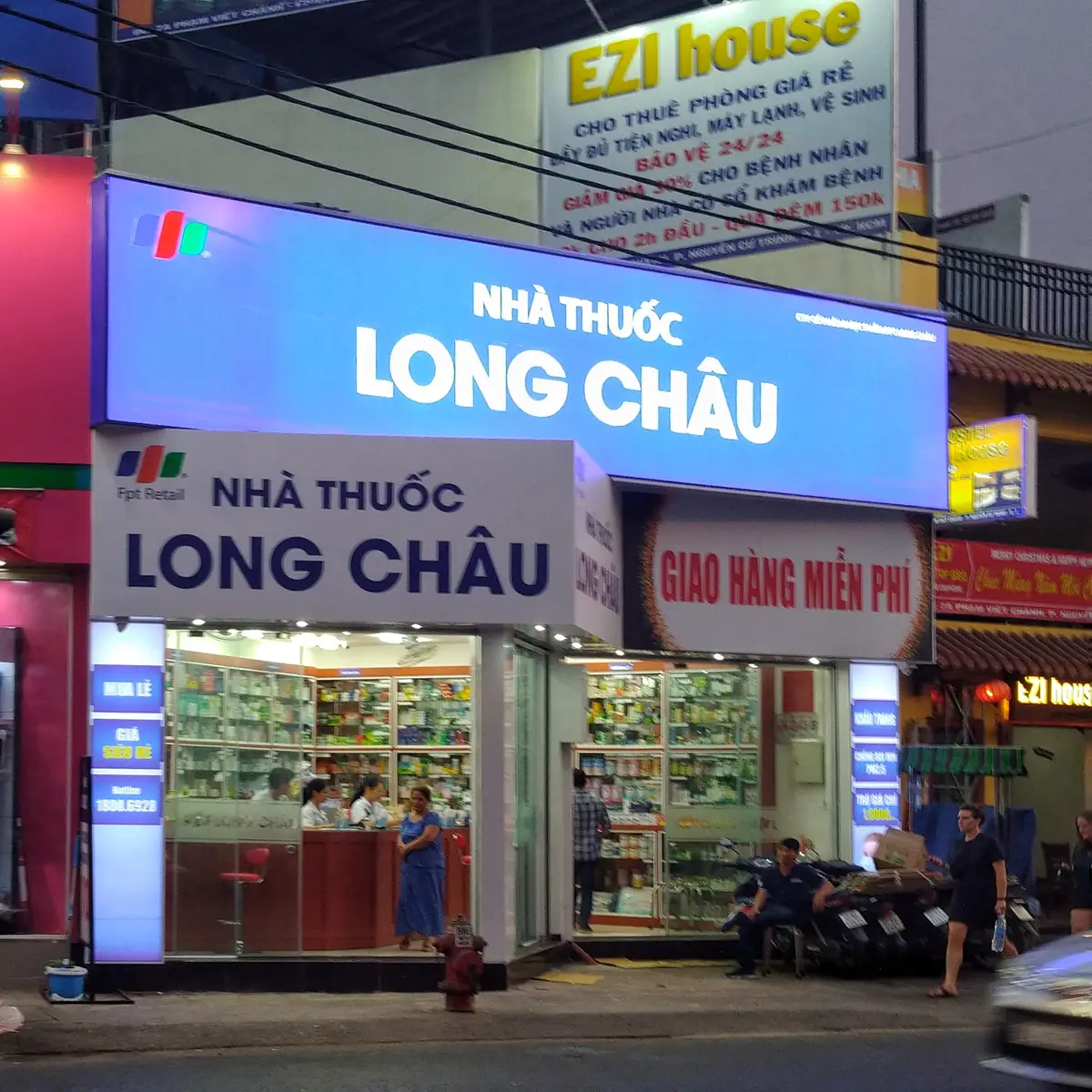 Blue Long Chau pharmacy sign above a shopfront with a free delivery panel.
