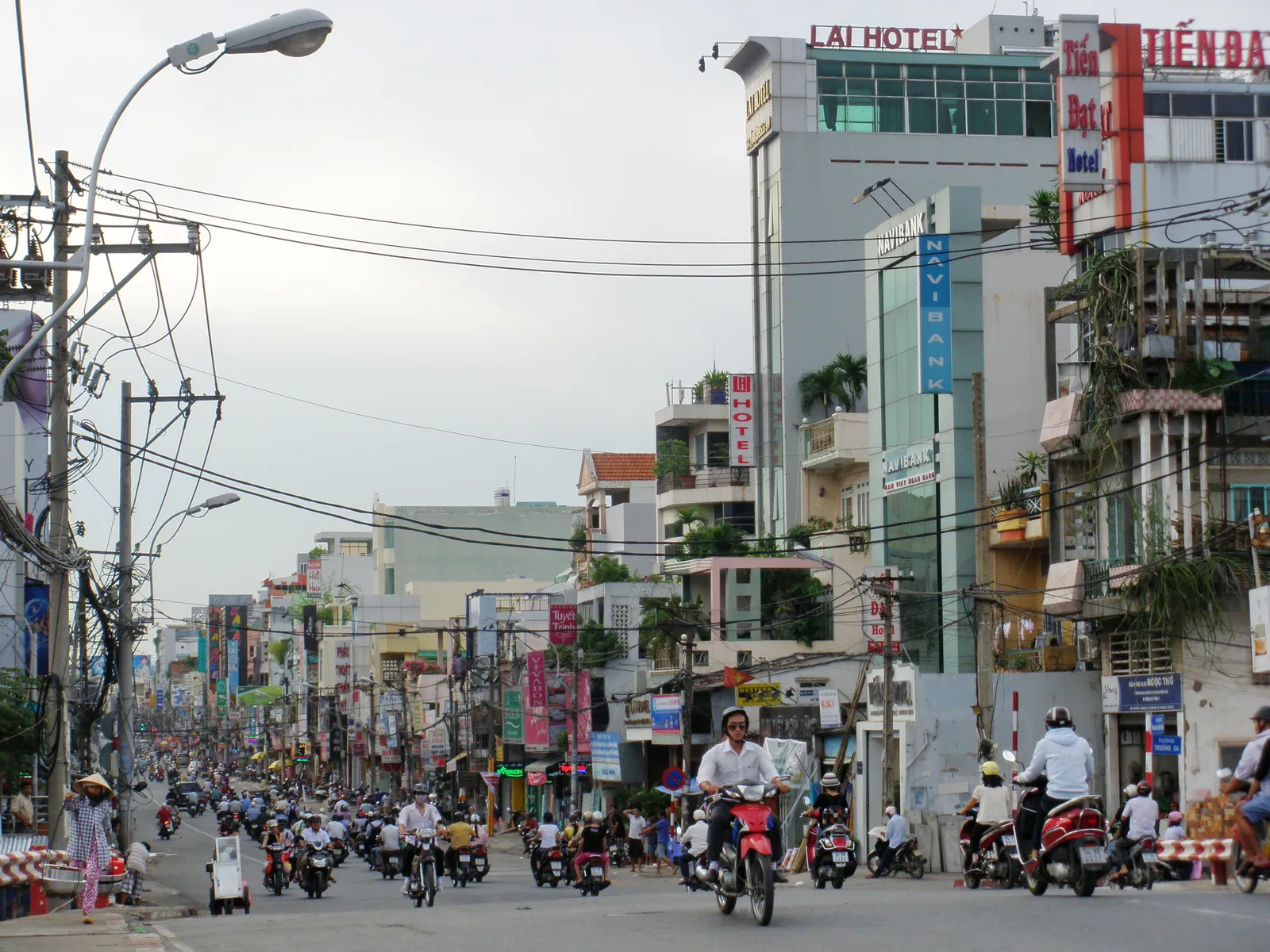 Busy street with motorbike riders and a hotel sign