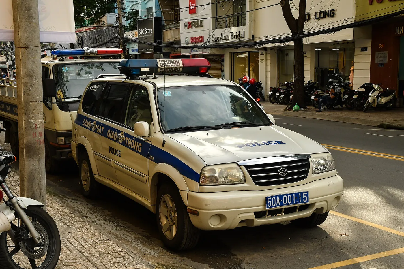 White traffic police SUV with a blue stripe parked at the kerb of a Ho Chi Minh City street
