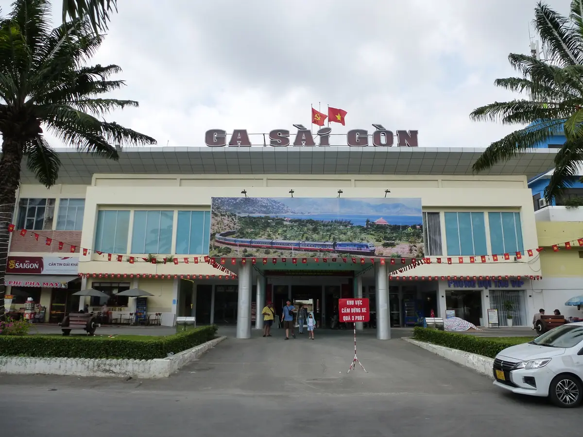 Cream station building with the Ga Sai Gon sign above the entrance, palm trees and a parked car