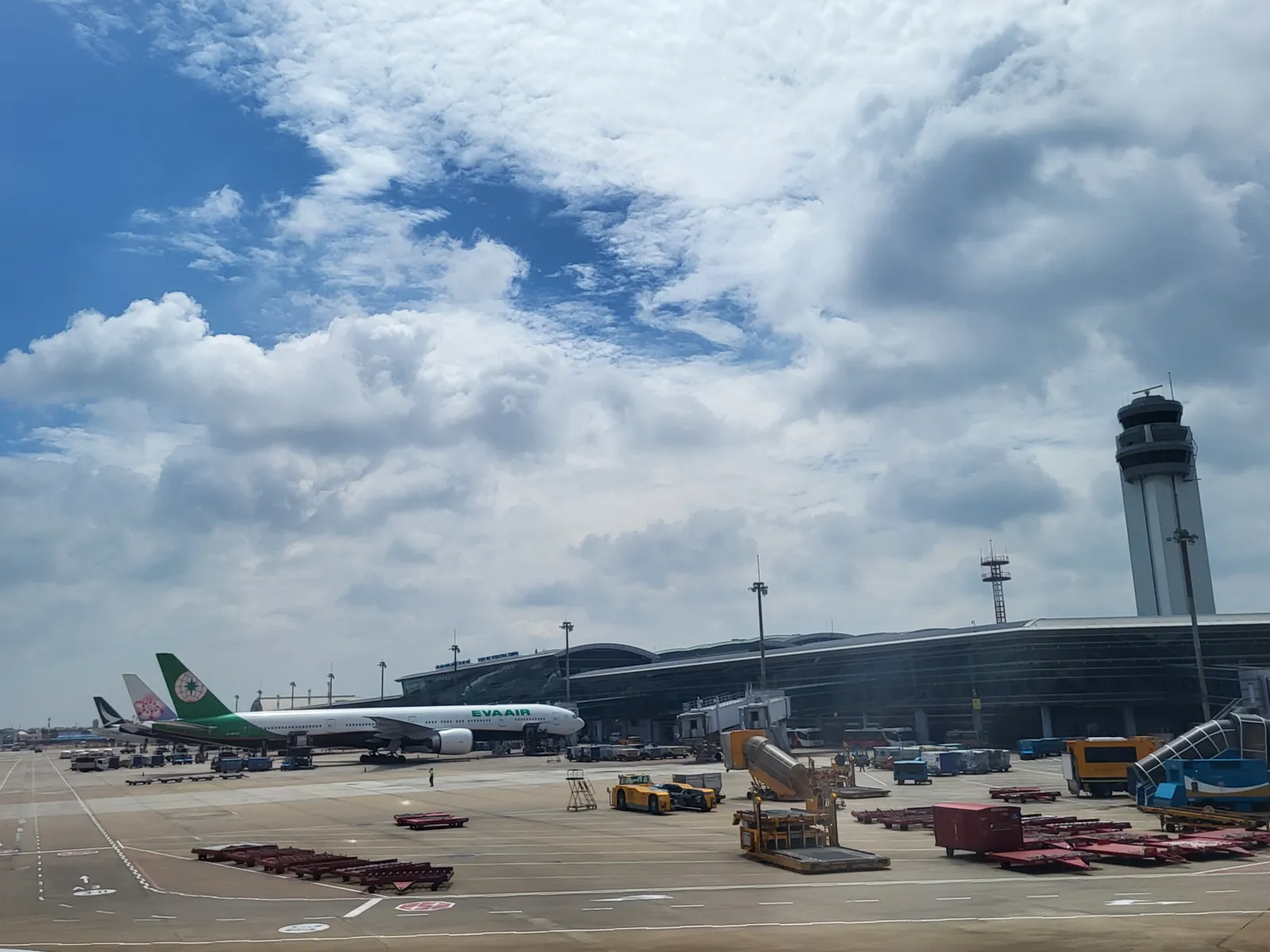 Airfield with parked jets and a control tower beyond the long roofline of an airport terminal
