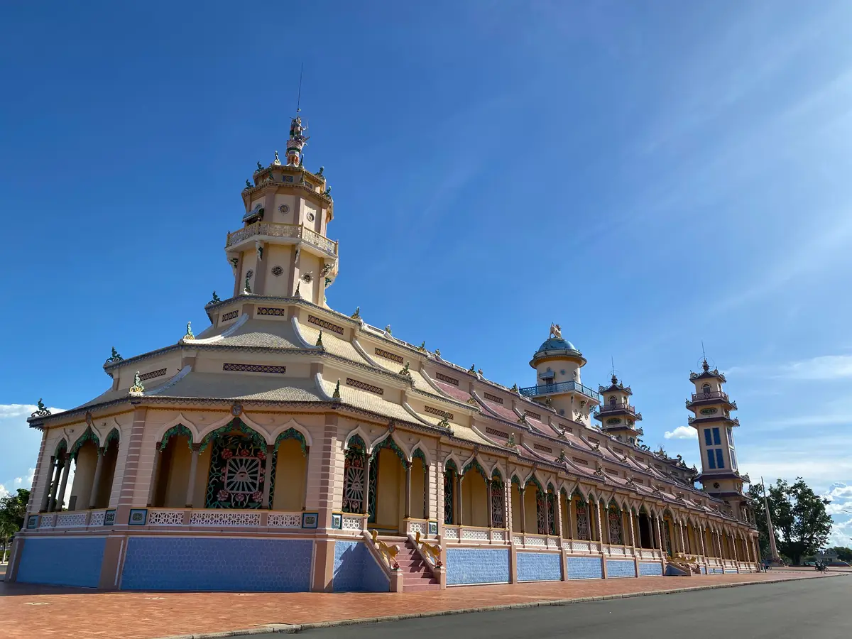 Long temple facade with arched windows, two towers and a blue sky behind