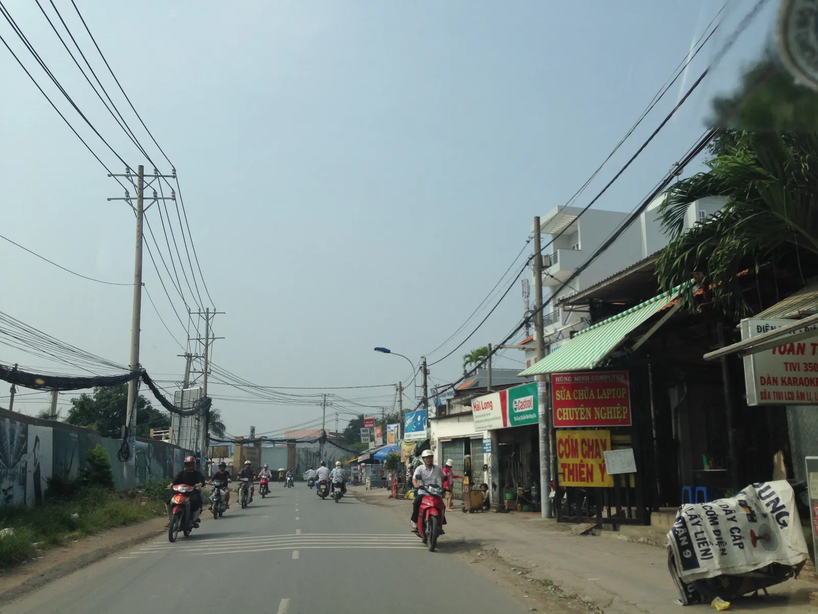 Straight local road lined with small shops and power lines
