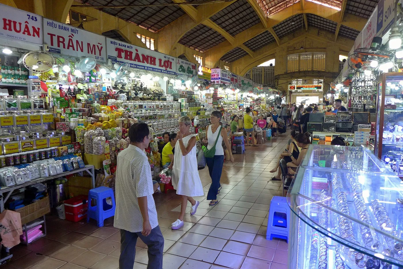 Inside the covered hall of Ben Thanh Market with stalls and shoppers under a high roof