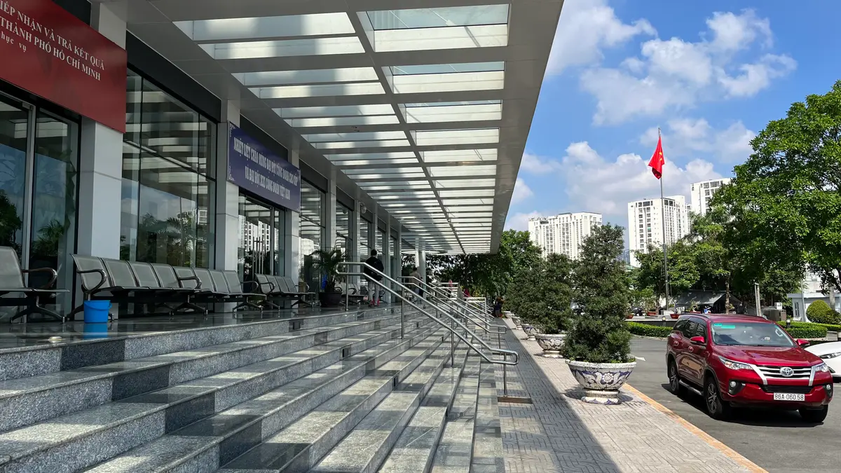 Covered entrance walkway with wide granite steps and a rail, and a red flag in the background.