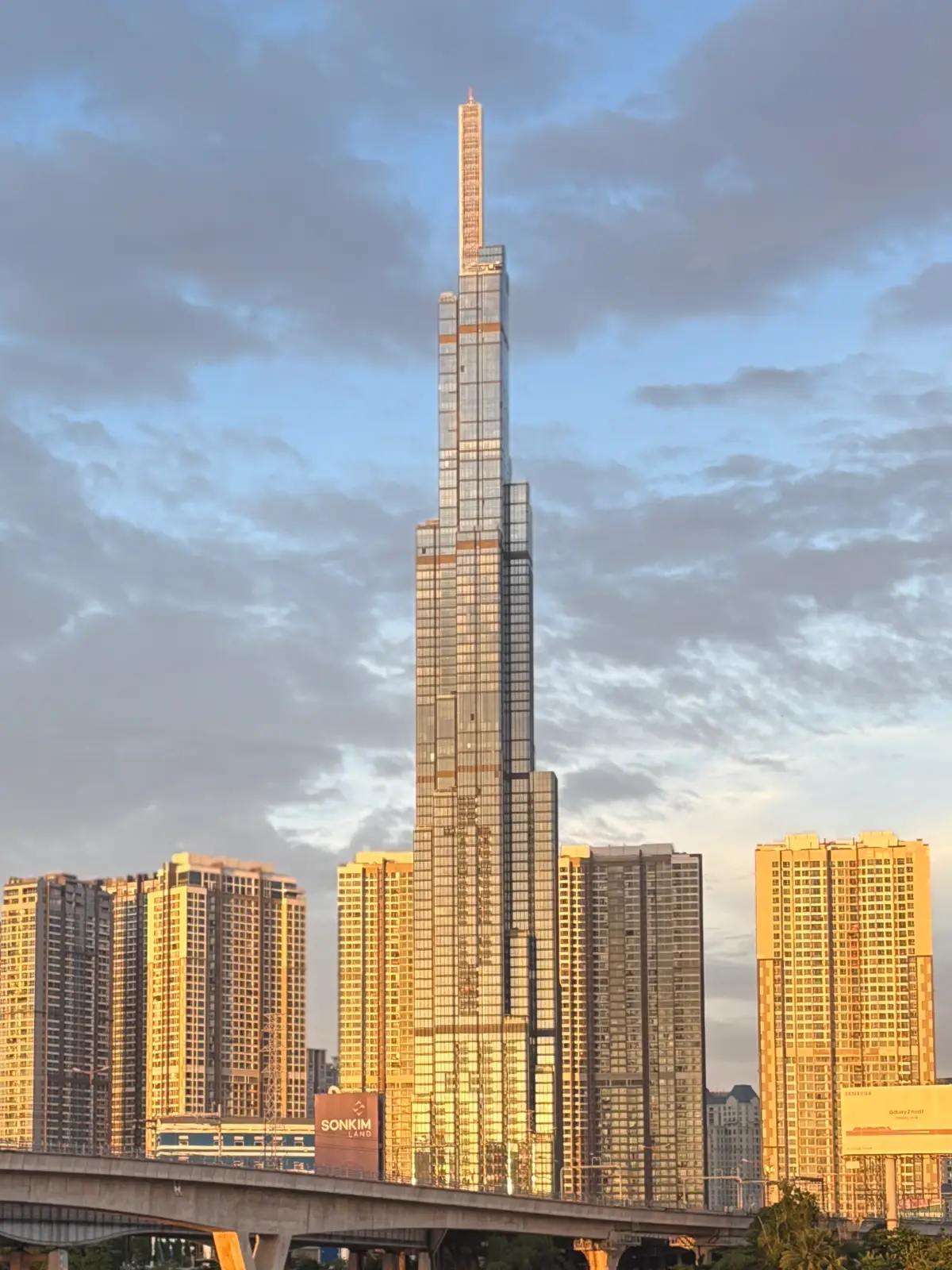 Tall glass tower rising behind apartment blocks under a cloudy sky